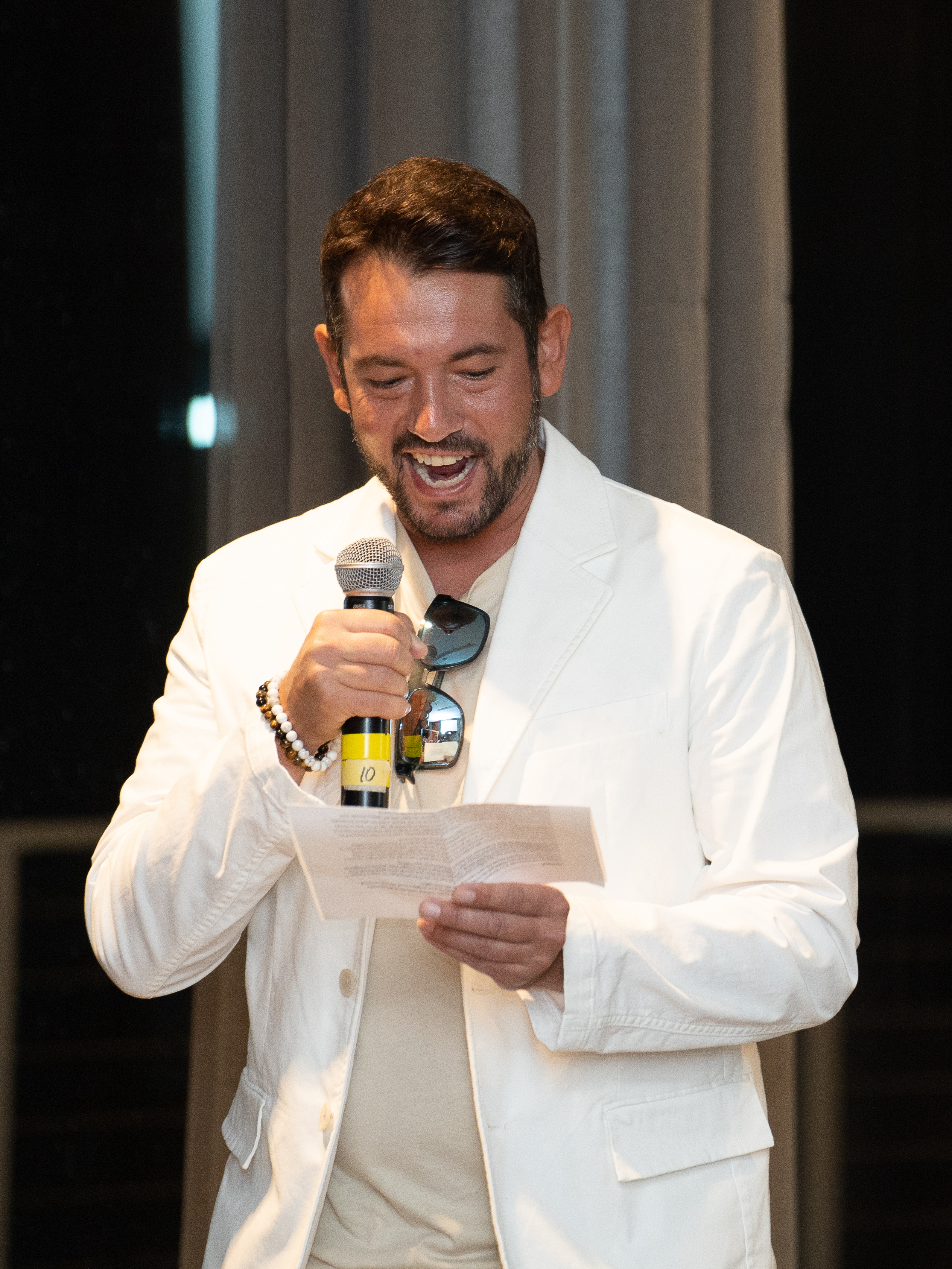 Alan giving a speech in a white blazer